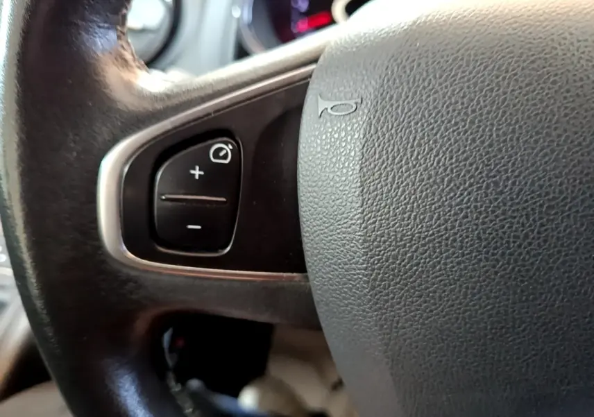 Gros plan sur le volant cuir noir de la Renault Clio Zen Energy dCi 75, avec commandes multifonctions visibles.