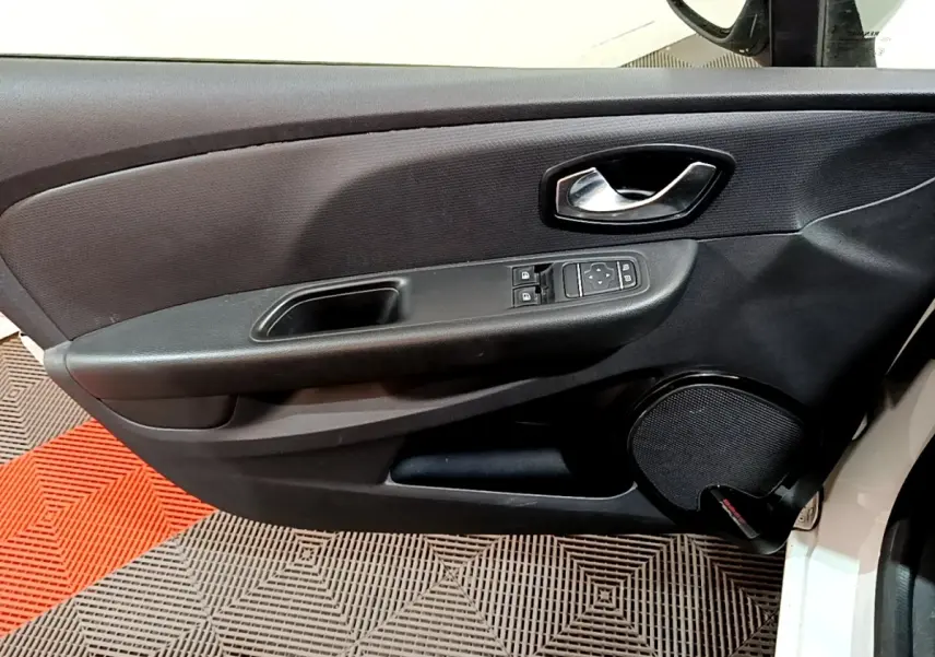 Vue intérieure du panneau de porte avant gauche d'une Renault Clio blanche, avec commandes électriques et haut-parleur intégré.