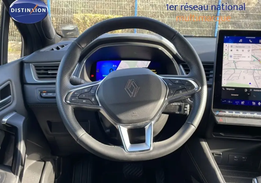 Vue intérieure centrée sur le volant noir du Renault Symbioz 2025, avec tableau de bord digital et écran tactile latéral.