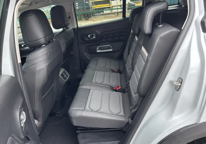 Vue latérale droite sur l’intérieur arrière du Citroën C5 Aircross blanc, montrant les trois sièges individuels gris et noirs.