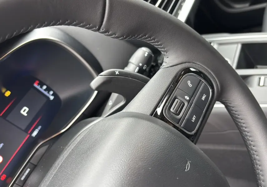 Gros plan sur le volant cuir multifonctions côté gauche du Citroën C5 Aircross Hybrid blanc, avec palettes au volant visibles.