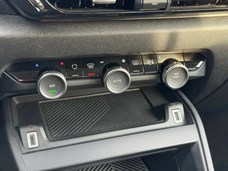Gros plan sur la console centrale du Citroën C4 X 2025, montrant les commandes de climatisation avec finition noire brillante.