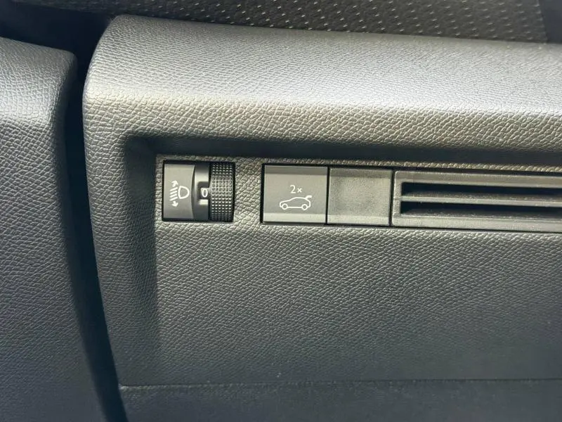 Détail intérieur montrant les commandes de réglage des phares et ouverture du coffre sur Citroën C4 X 2025.