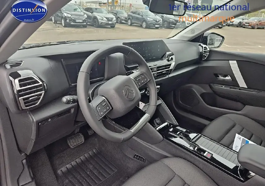 Intérieur avant droit de la Citroën C4 1.2 hybride 136 plus avec tableau de bord noir et volant cuir.