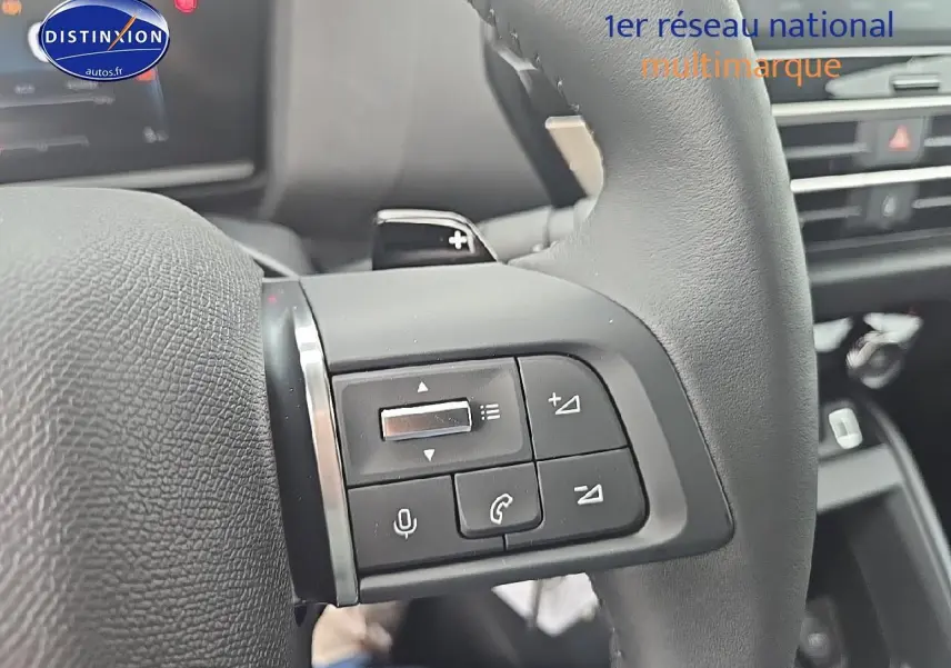 Gros plan sur les commandes audio et téléphone au volant en cuir noir de la Citroën C4 1.2 hybride 136 plus 2025.
