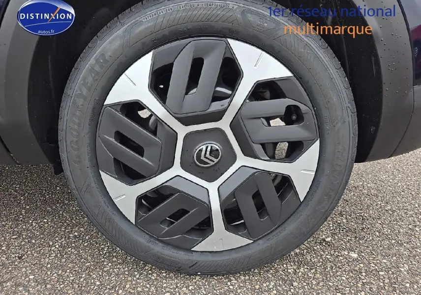 Gros plan sur la roue avant gauche avec jante noire et argentée du Citroën C4 bleu eclipse 2025 hybride.