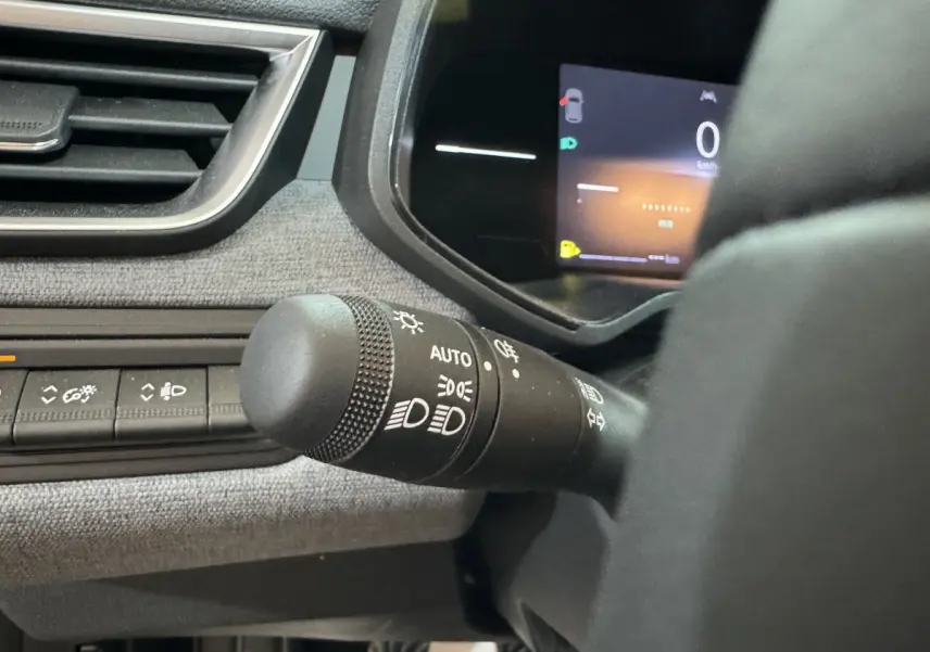 Gros plan sur la commande des phares et le combiné d'instruments numérique de la Renault Clio gris clair 2025.