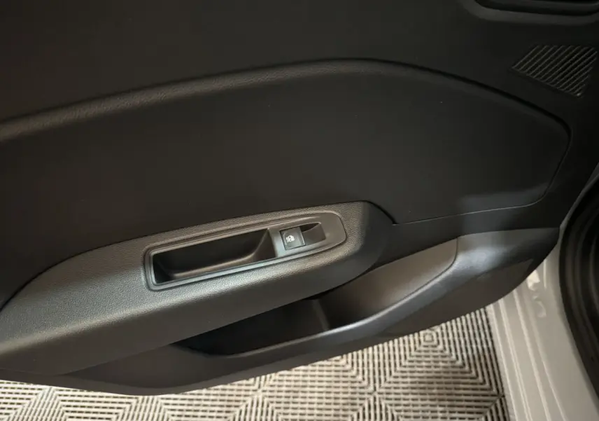 Gros plan sur la poignée intérieure côté gauche d'une Renault Clio gris clair, avec bouton de verrouillage des portes.