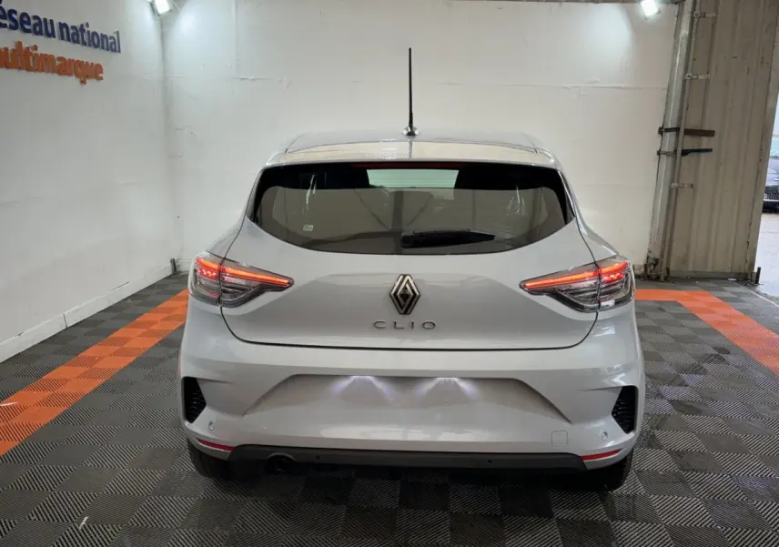 Vue arrière d'une Renault Clio gris clair 2025 avec feux LED allumés dans un garage éclairé