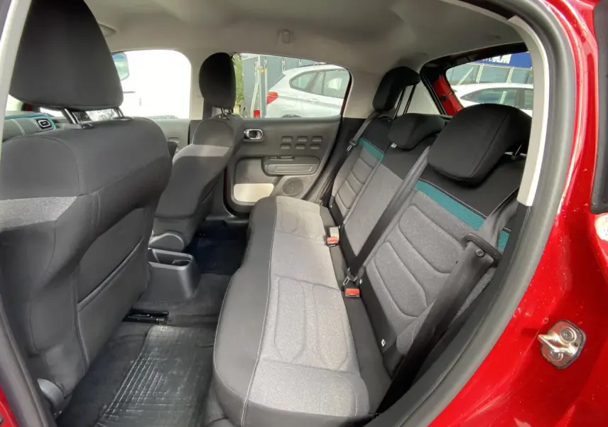 Vue intérieure côté droit de la banquette arrière grise avec ceinture et porte rouge vif d'une Citroën C3 Shine 2021.