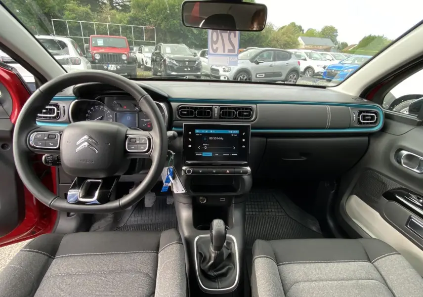 Vue intérieure avant de la Citroën C3 2021 rouge, volant multifonction et tableau de bord avec écran tactile central.