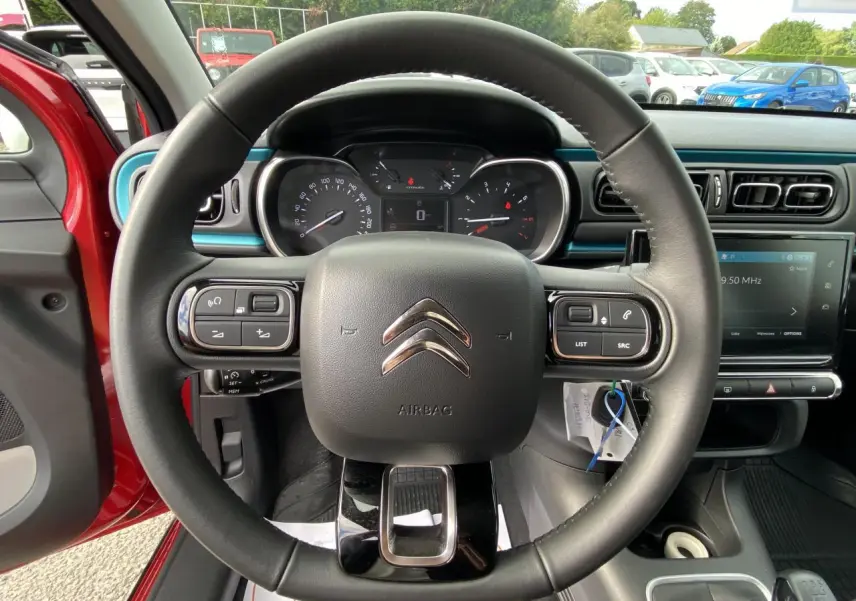 Vue rapprochée du volant noir de la Citroën C3 2021 avec tableau de bord et écran tactile en arrière-plan.