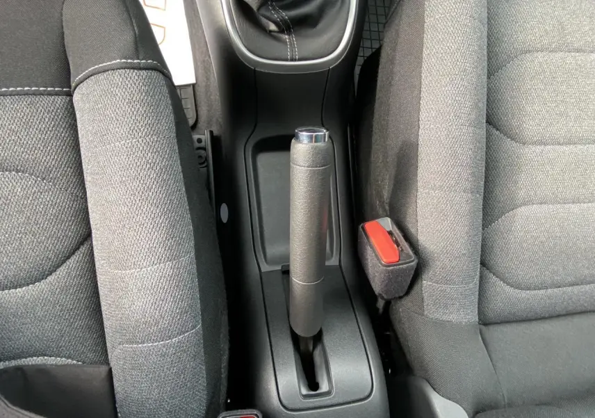 Vue rapprochée du frein à main manuel entre les sièges avant gris foncé d'une Citroën C3 1.2 PureTech essence.