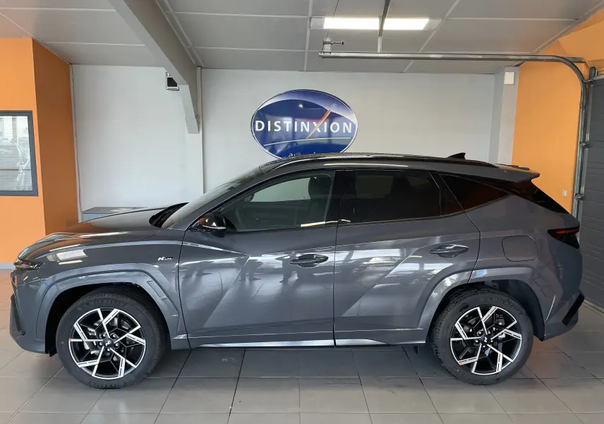 Vue de profil côté gauche d'un Hyundai Tucson gris Ecotronic 2025 en finition N Line dans un showroom.
