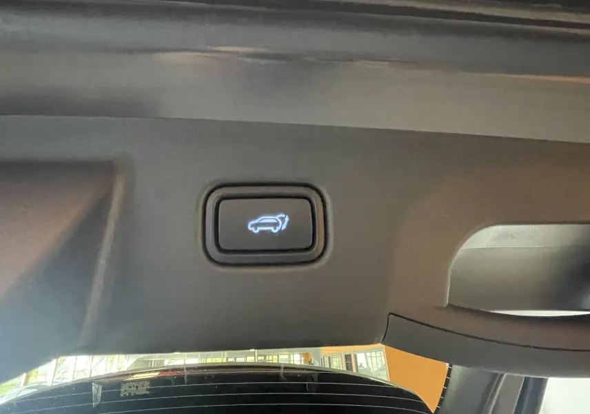 Bouton d'ouverture électrique du coffre sur le hayon intérieur d'un Hyundai Tucson gris Ecotronic 2025.