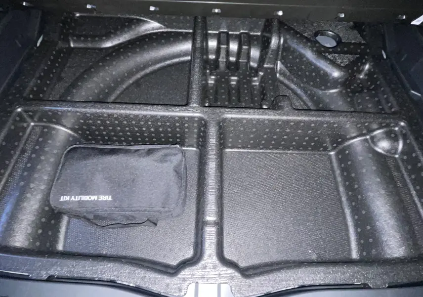Compartiment de rangement sous le coffre du Hyundai Tucson gris Ecotronic 2025, avec kit de mobilité pneus visible.