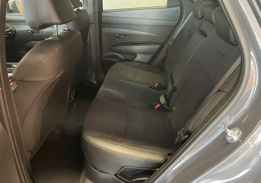 Vue côté droit de l'habitacle arrière du Hyundai Tucson gris Ecotronic, sièges noirs avec surpiqûres rouges et garnitures cuir-alcantara.