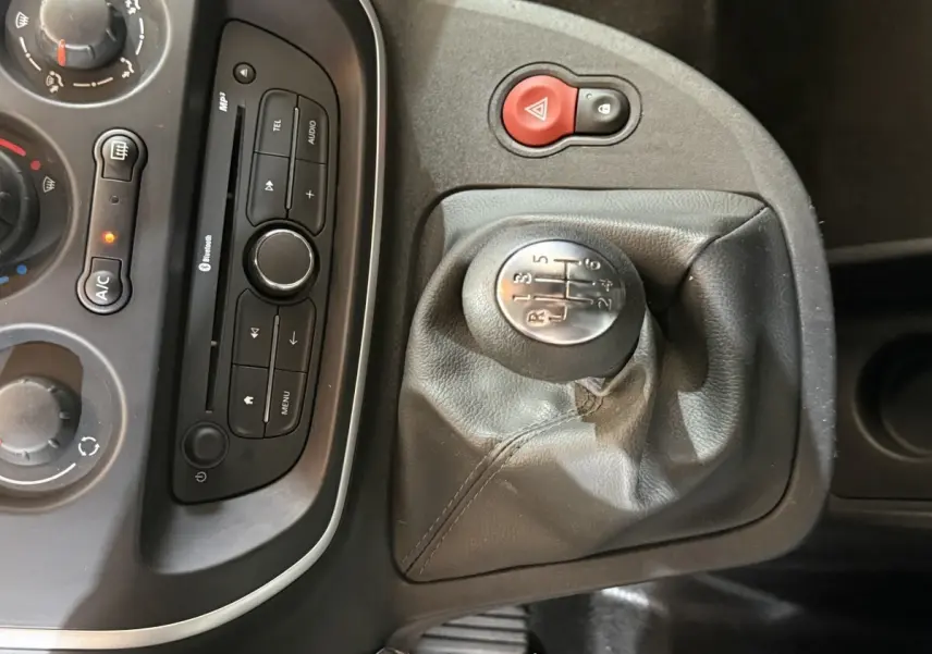 Gros plan sur la console centrale du Renault Kangoo blanc, mettant en valeur le levier de vitesses manuel et les commandes audio.