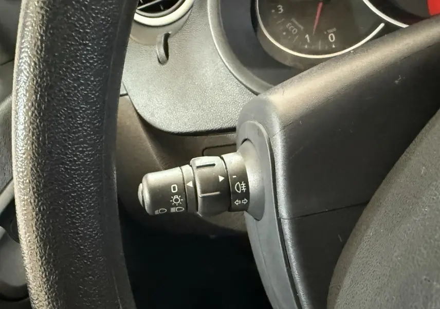 Gros plan sur la manette des phares à gauche du volant noir dans l’habitacle du Renault Kangoo blanc 2021.