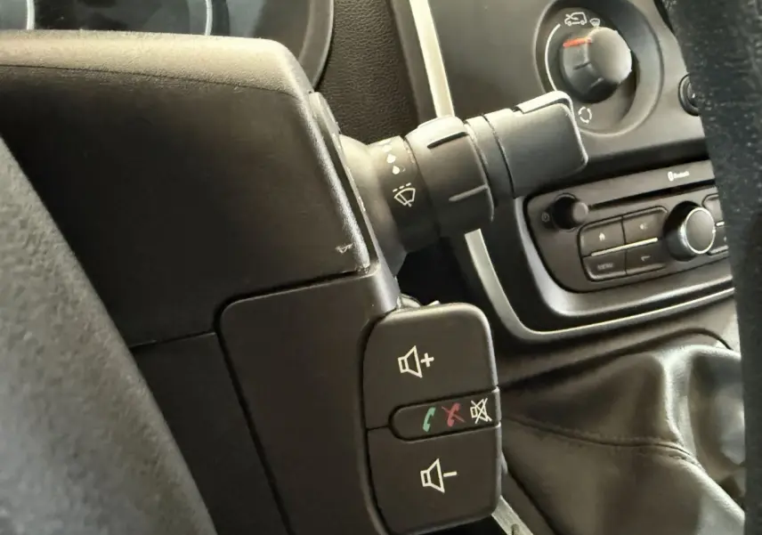 Gros plan sur les commandes au volant et la console centrale noire du Renault Kangoo Extra R-Link 2021, intérieur sombre.