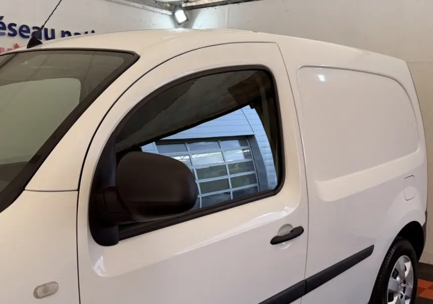 Vue de profil droit d’un utilitaire Renault Kangoo blanc avec porte latérale pleine et rétroviseur noir.