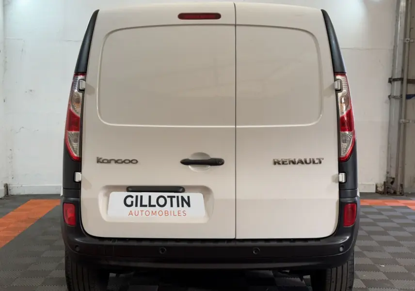 Vue arrière d’un Renault Kangoo blanc avec portes battantes et pare-chocs noir dans un garage.