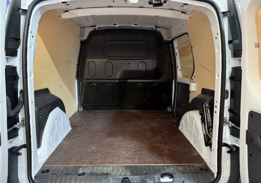 Vue intérieure arrière du Renault Kangoo blanc 2021, montrant l'espace de chargement vide avec cloison pleine et plancher en bois.