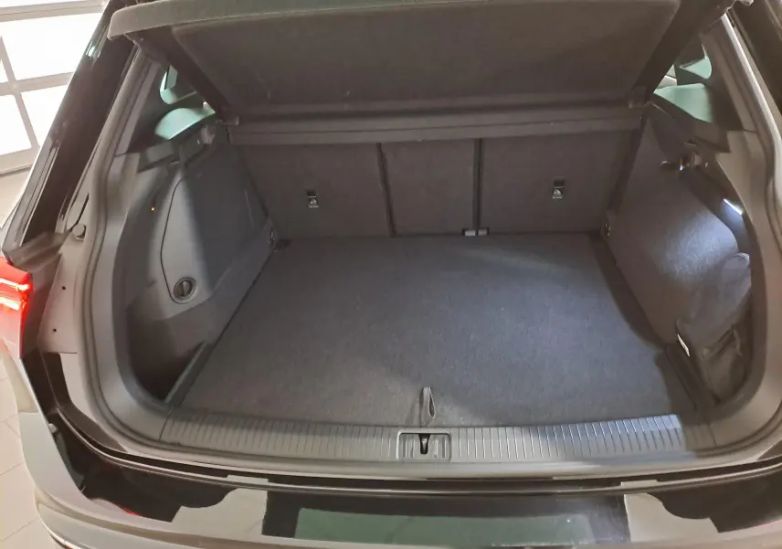 Coffre ouvert du Volkswagen Tiguan 1.4 eHybrid noir intense nacré, vue arrière montrant l’espace de chargement vide.