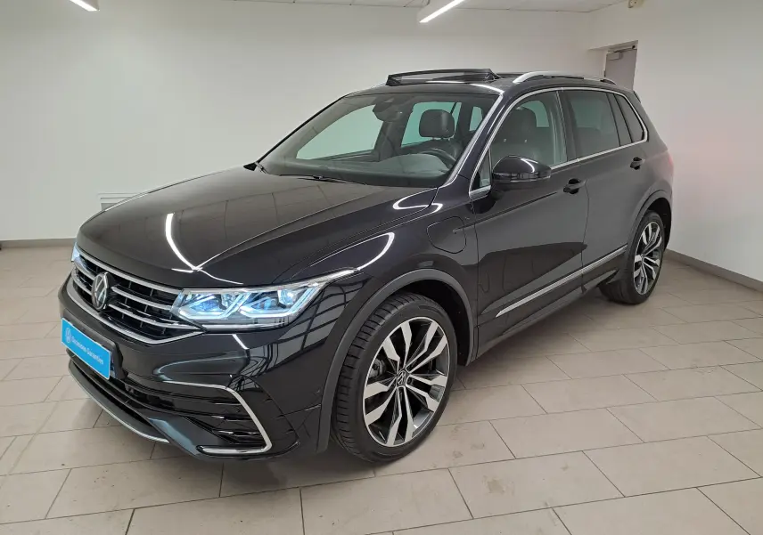 Volkswagen Tiguan 1.4 eHybrid noir intense nacré, vue 3/4 avant droit avec jantes 20'' Suzuka et phares allumés.
