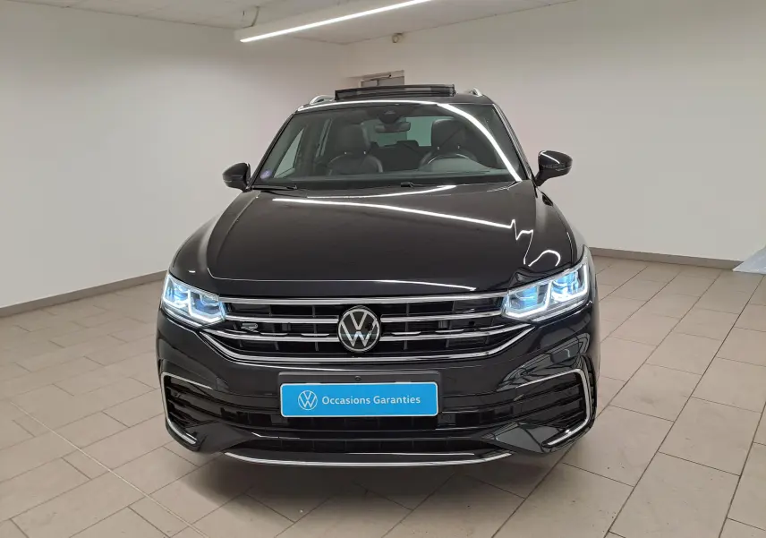 Vue avant d'un Volkswagen Tiguan 1.4 eHybrid noir intense nacré avec phares LED allumés en intérieur.
