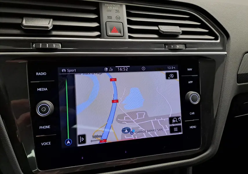 Vue rapprochée de l'écran tactile central du Volkswagen Tiguan 2023 avec navigation affichée, entouré de commandes noires.