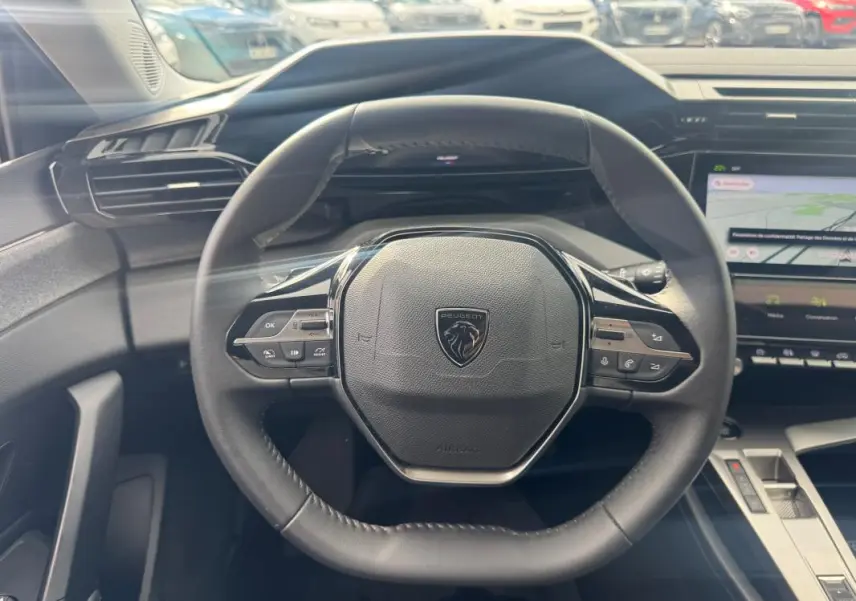 Vue centrée sur le volant noir du Peugeot 308 Hybrid 145 Allure 2025 avec tableau de bord numérique et écran tactile.