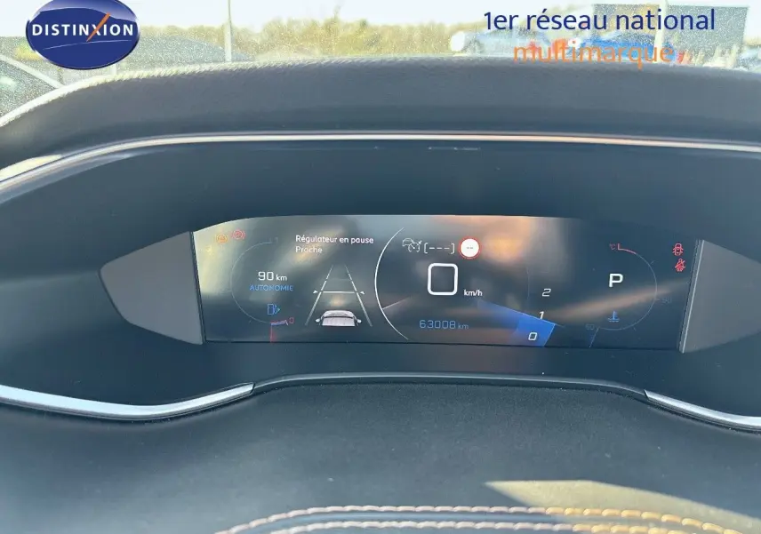 Affichage numérique du tableau de bord de la Peugeot 308 blanc nacré, montrant la vitesse à 0 km/h et l'autonomie restante.