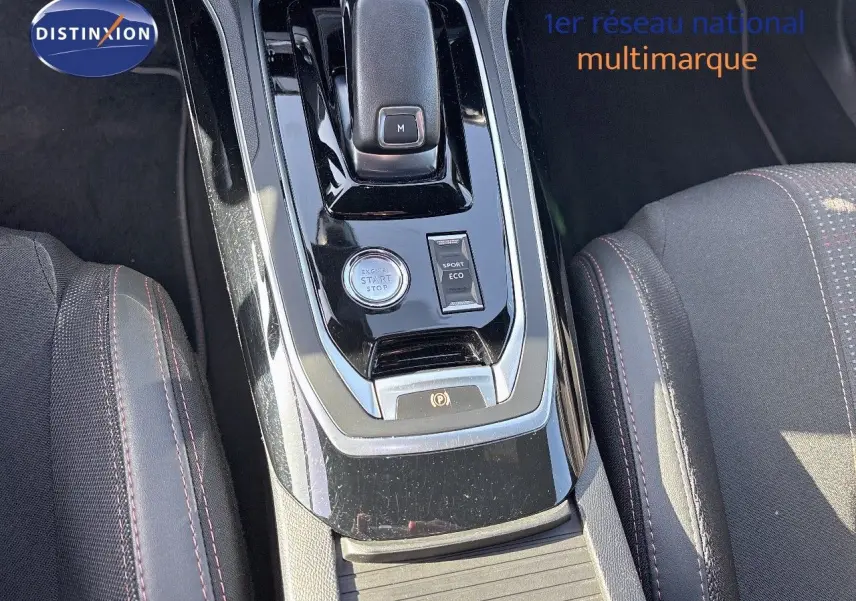 Gros plan sur la console centrale noire brillante de la Peugeot 308 blanche nacrée, avec levier de vitesse et boutons start/stop.