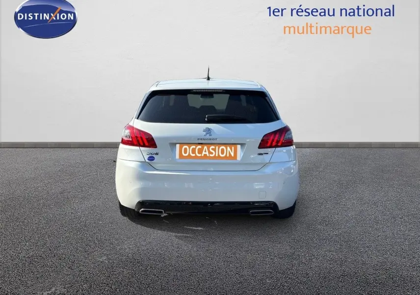 Vue arrière d'une Peugeot 308 GT blanche nacrée de 2021, avec feux rouges et double sortie d'échappement visible.