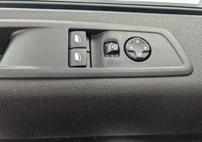 Gros plan sur les commandes noires des vitres et rétroviseurs sur la portière intérieure du Peugeot Expert Fourgon blanc 2024.