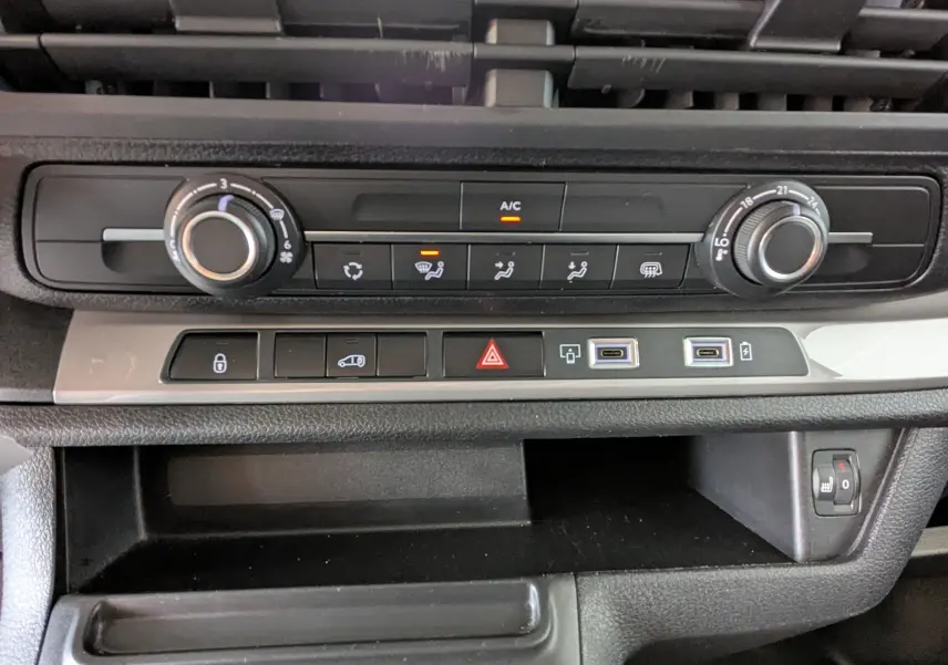 Vue rapprochée de la console centrale du Peugeot Expert Fourgon blanc 2024, avec commandes climatisation et ports USB.