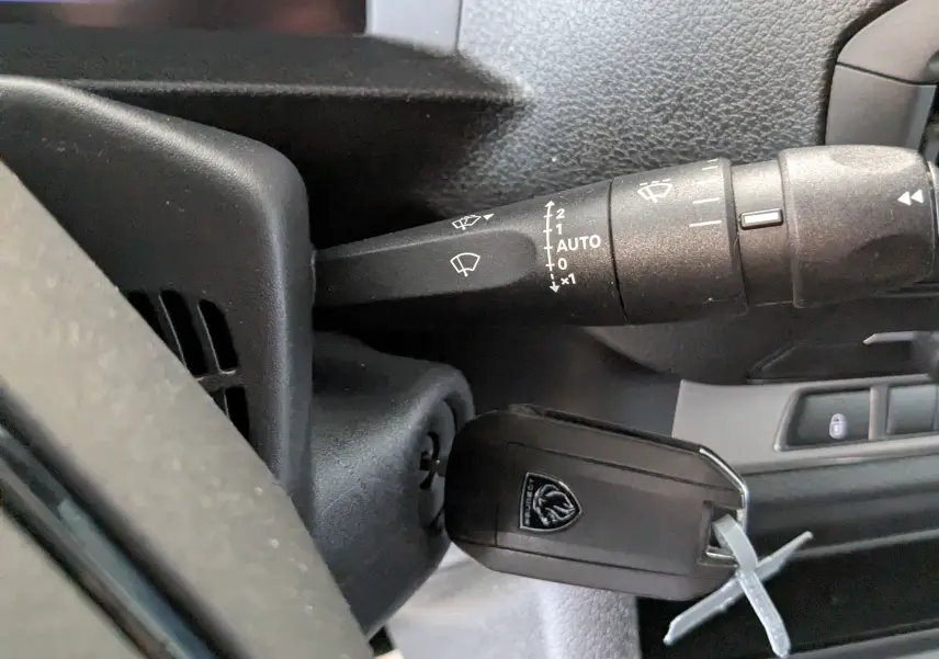 Gros plan sur la commande d’essuie-glace et la clé de contact du Peugeot Expert Fourgon blanc, tableau de bord partiel visible.