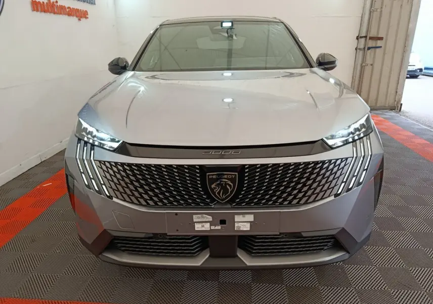 Vue frontale du Peugeot 3008 gris clair 2025 avec calandre distinctive et phares LED en forme de griffes.