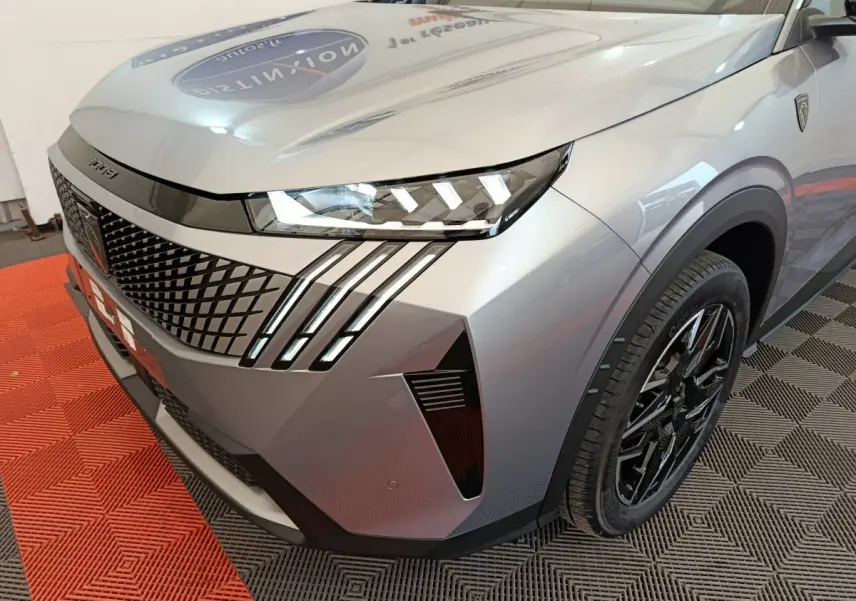 Vue 3/4 avant droit du Peugeot 3008 gris clair avec phares LED et signature lumineuse distinctive en griffes.