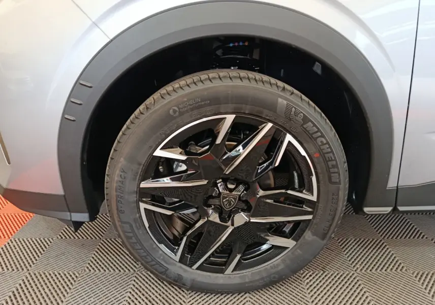 Gros plan sur la jante noire et argentée du côté avant droit d’un Peugeot 3008 gris clair hybride 2025.