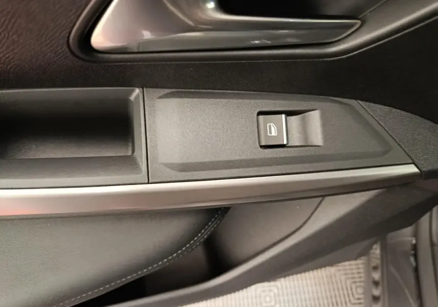 Détail intérieur montrant la garniture de porte en cuir noir et les finitions métalliques du Peugeot 3008 gris clair.