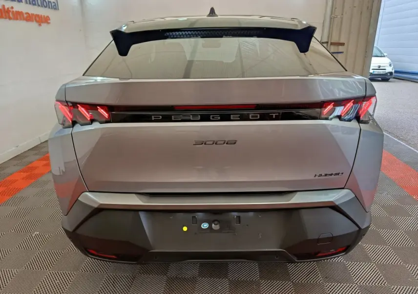 Vue arrière d'un Peugeot 3008 gris clair hybride 2025 avec feux LED caractéristiques et logo central lumineux.