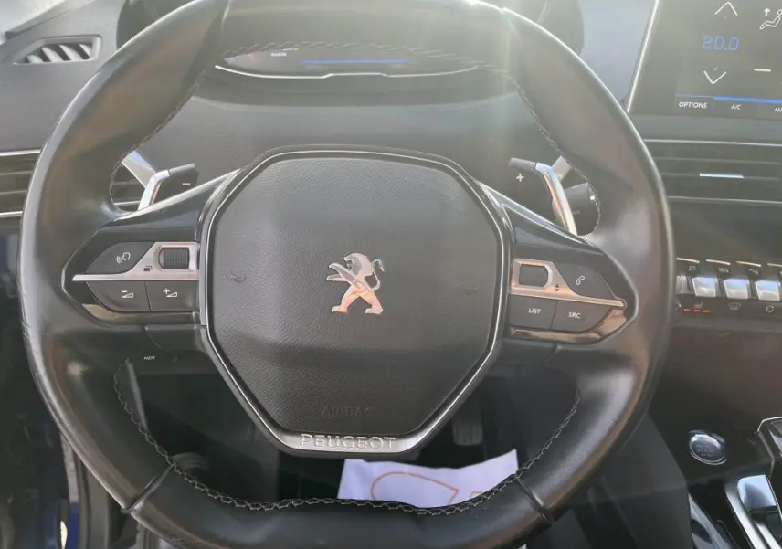 Vue rapprochée du volant compact noir du Peugeot 3008 2020 avec commandes intégrées et logo lion central chrome.