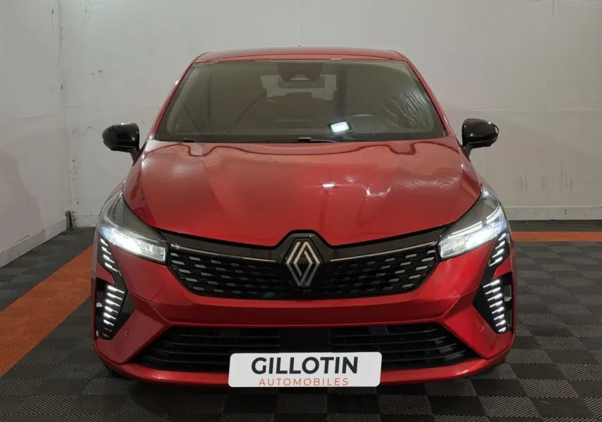 Vue frontale d'une Renault Clio Techno TCe 90 rouge avec feux LED allumés dans un garage.