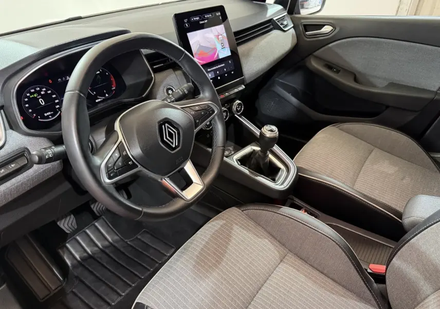 Intérieur Renault Clio Techno TCe 90 2024 vu côté conducteur, volant cuir, écran tactile vertical et sièges gris.