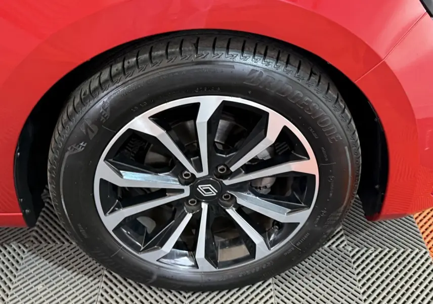 Gros plan sur la roue avant droite d'une Renault Clio Techno TCe 90 rouge, jante alliage noire et argent.