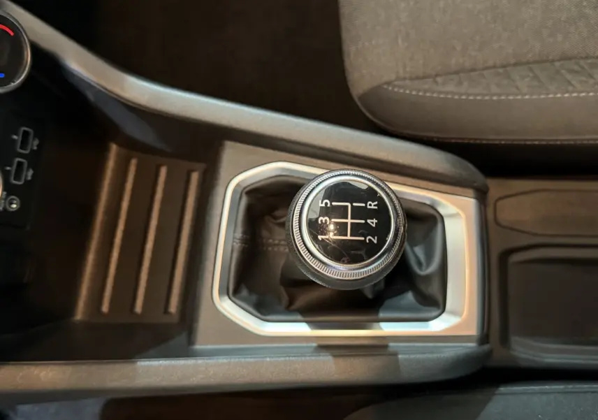 Vue rapprochée de la boîte manuelle noire et argentée de la Renault Clio Business blanche, avec siège tissu gris visible.