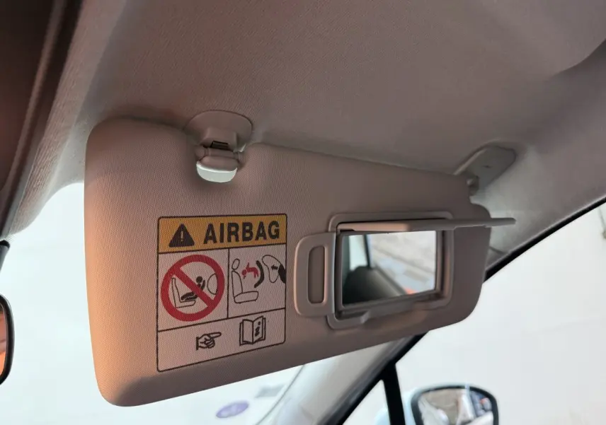 Détail du pare-soleil côté conducteur de la Renault Clio blanc 2021 avec miroir de courtoisie ouvert et avertissement airbag.