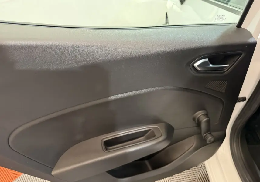 Vue intérieure côté gauche de la porte avant d'une Renault Clio blanche 2021 avec poignée manuelle de vitre.